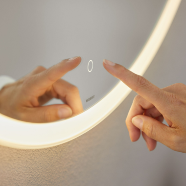 Întrerupător cu senzor tactil de acționare manuală pe oglinda Geberit Option Round (© Geberit)