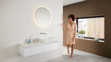 Femeie într-o baie modernă cu o schemă de culori maro - cea mai recentă tendință în materie de culori pentru băi - și o combinație de lavoare Mix & Match Femeie într-o baie modernă cu o schemă de culori maro - cea mai recentă tendință în materie de culori pentru băi - și o combinație de lavoare Mix & Match