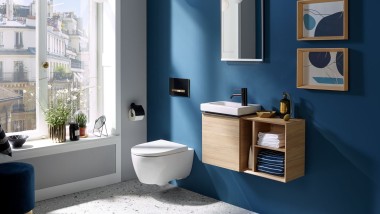 Lumina care intră printr-o fereastră într-un WC pentru oaspeți cu un perete din spate albastru închis