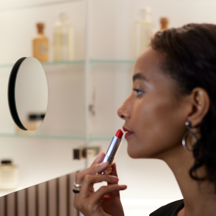 Femeie care aplică machiaj în oglindă