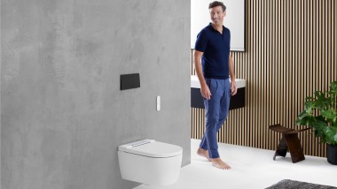 Bărbat în baie privind zona WC cu o toaletă Geberit
