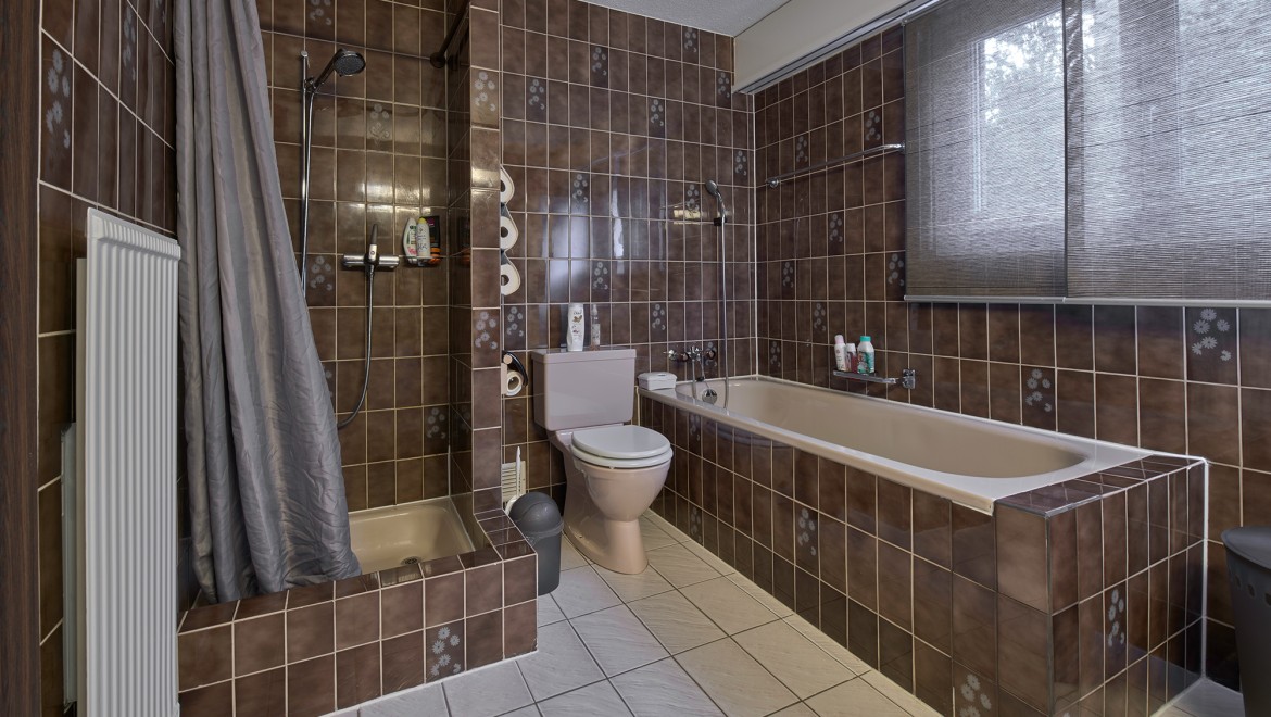 Baie cu colț de duș îngust, cadă și WC pe podea Baie cu colț de duș îngust, cadă și WC pe podea