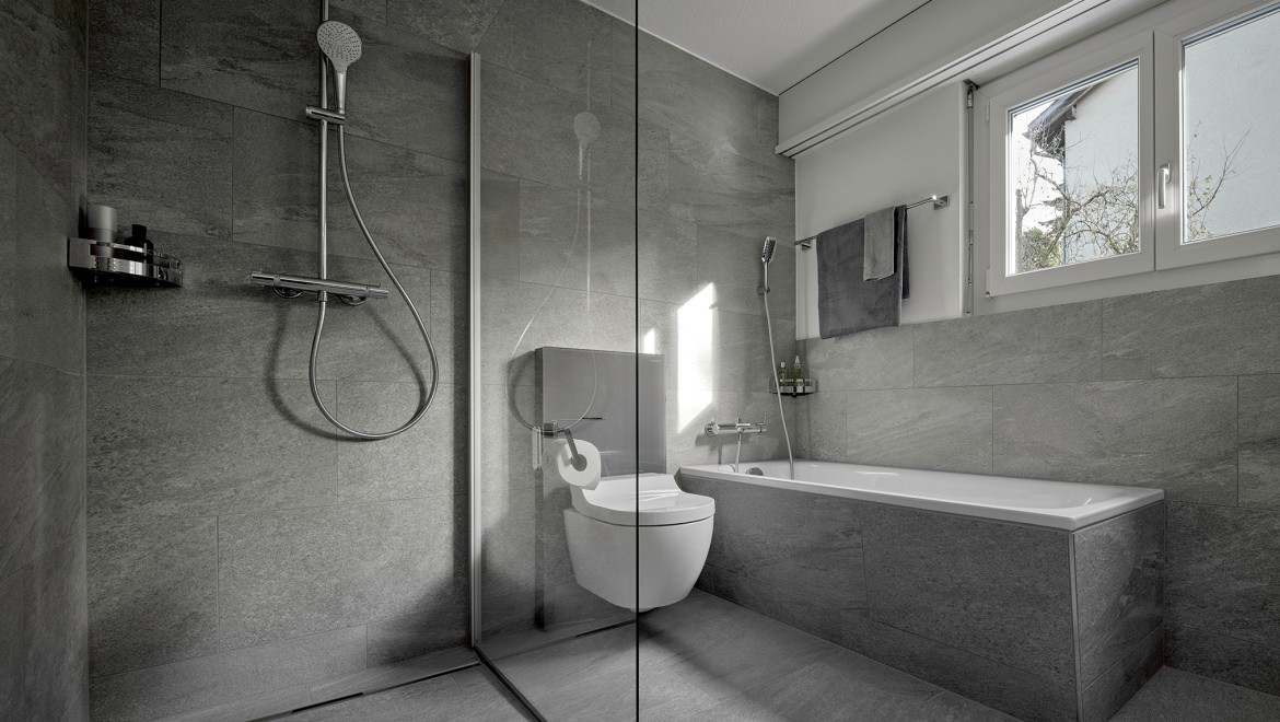 Un vas wc cu funcție de bideu între un duș la nivel cu podeaua și o cadă de baie Un vas wc cu funcție de bideu între un duș la nivel cu podeaua și o cadă de baie