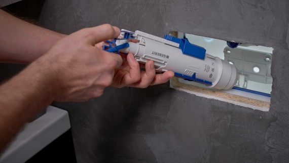 Un bărbat instalează o supapă de spălare Geberit într-un rezervor de apă încastrat (© Ben Huggler) Un bărbat instalează o supapă de spălare Geberit într-un rezervor de apă încastrat (© Ben Huggler)