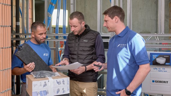 Un reprezentant de vânzări Geberit consiliază instalatori pe şantierul de construcţii Un reprezentant de vânzări Geberit consiliază instalatori pe şantierul de construcţii