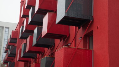 O fațadă roșie izbitoare cu balcoane cubice în față este noul punct de atracție de pe Goldsteinstrasse din Frankfurt am Main (DE) (© Geberit)