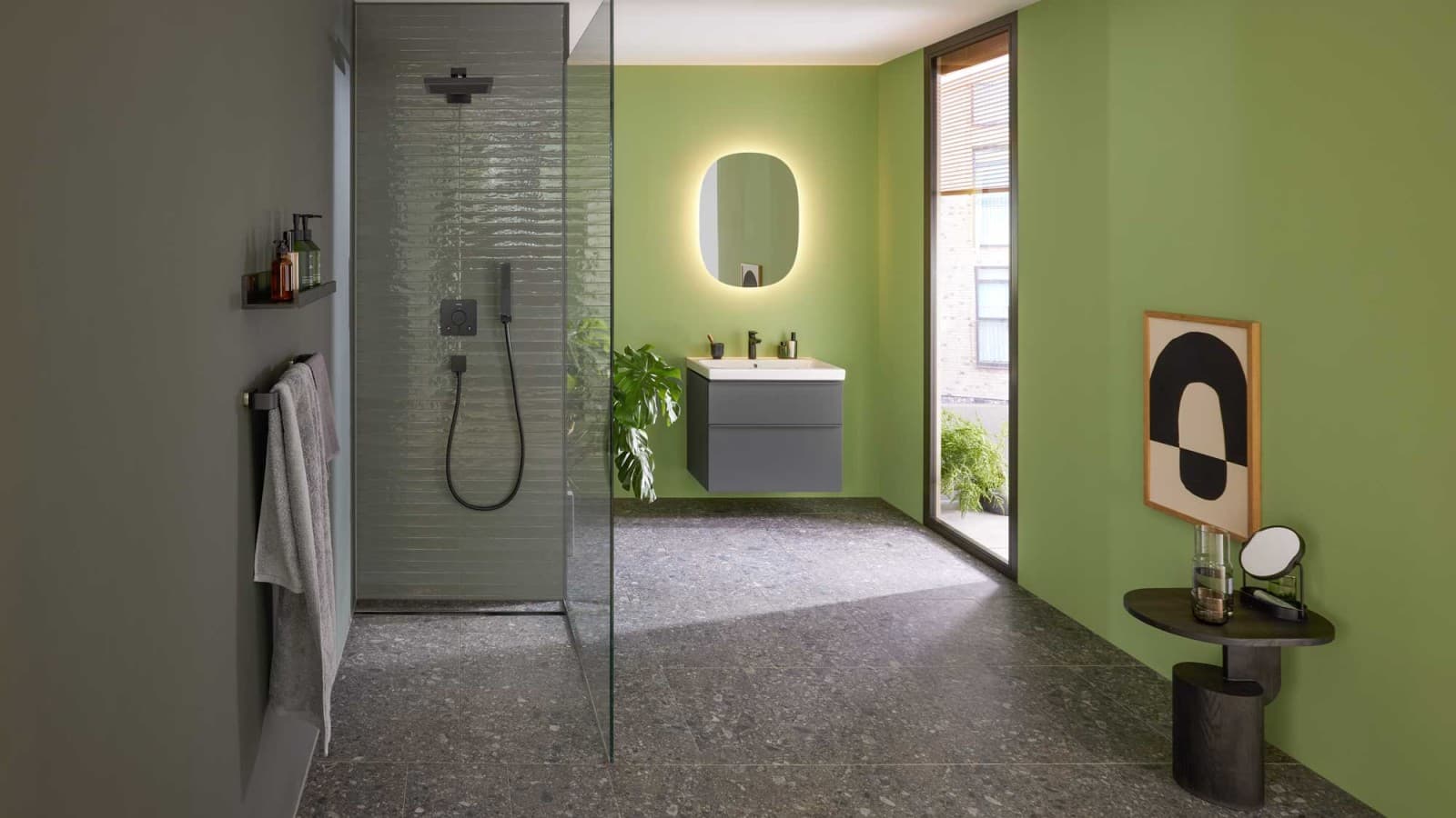 Baie în nuanțe de verde, dotată cu mobilier și obiecte sanitare Geberit iCon, o rigolă de duș Geberit CleanLine30 de culoare neagră și o oglindă ovală Geberit Option. Baie în nuanțe de verde, dotată cu mobilier și obiecte sanitare Geberit iCon, o rigolă de duș Geberit CleanLine30 de culoare neagră și o oglindă ovală Geberit Option.