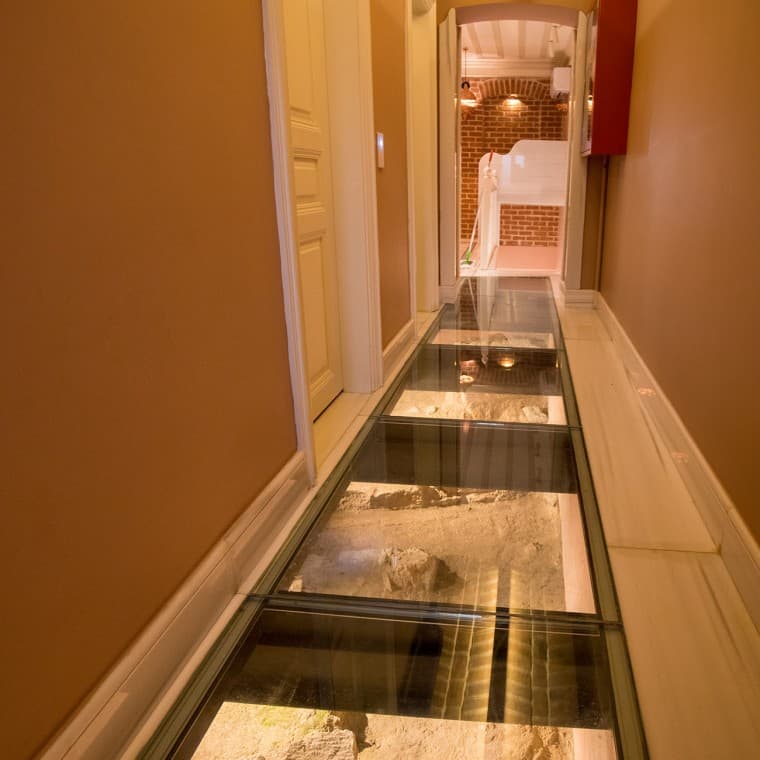 Pe coridoarele de la parter, rămășițele vechi ale zidului fostei grădini a palatului sunt vizibile sub plăcile de pardoseală vitrate. (© Hande Erçin) Pe coridoarele de la parter, rămășițele vechi ale zidului fostei grădini a palatului sunt vizibile sub plăcile de pardoseală vitrate. (© Hande Erçin)